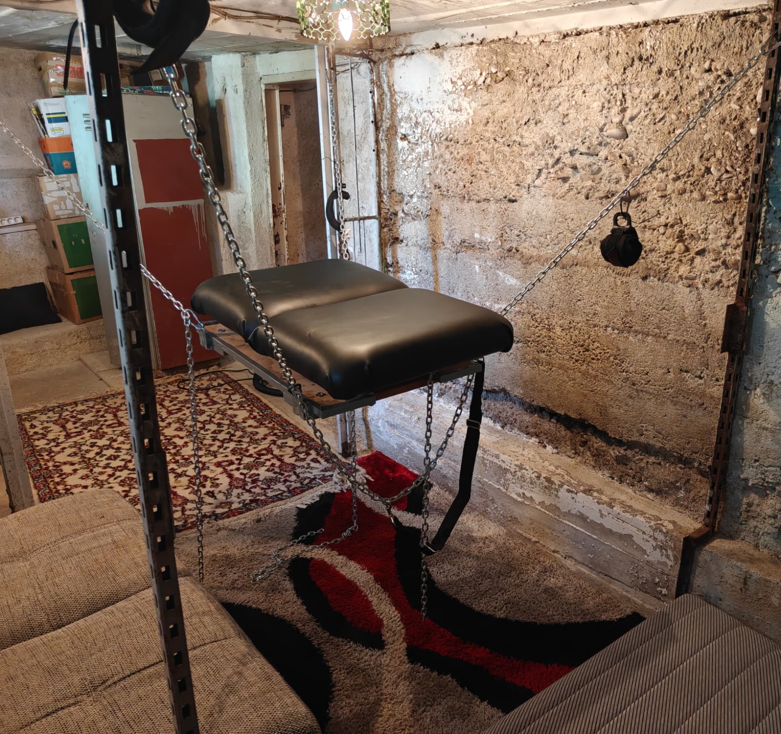 A leather sling suspended from chains in the dungeon